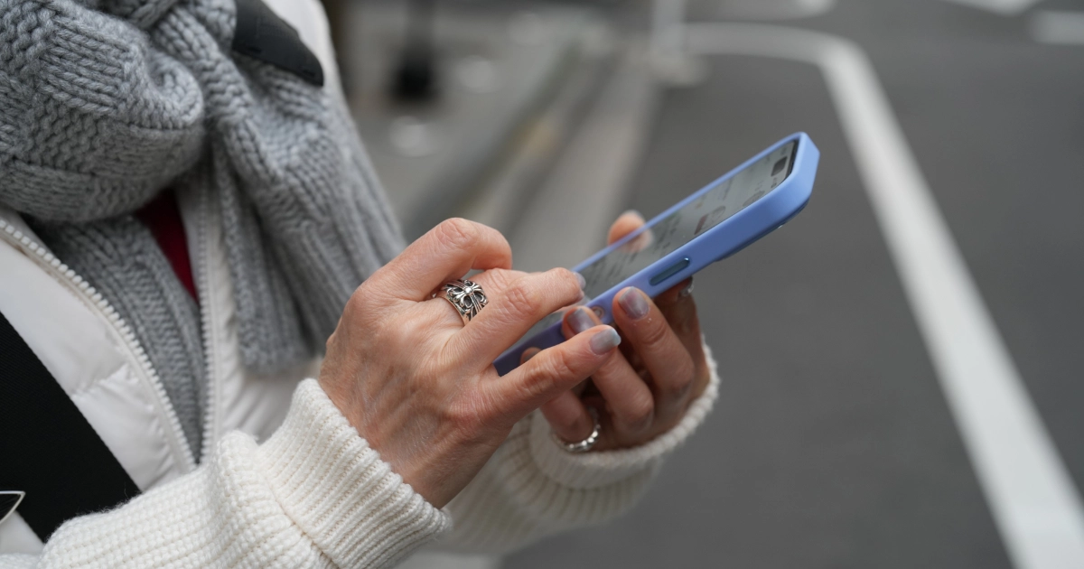 退去費用について両手でスマートフォンを使って調べている高齢者