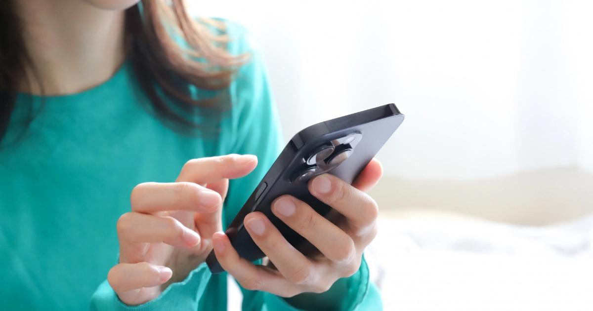 退去費用について両手でスマートフォンを使って調べている女性借主